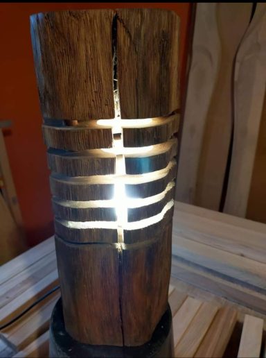 Holzlampe mit dekorativen Metallstreifen und sanftem Licht.